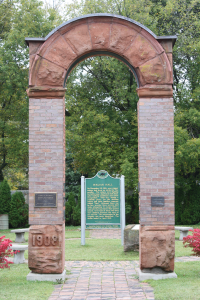 This photo of the Italian Hall memorial arch was taken in 2010.  The narrative sign in the background was recently updated to provide more historical information as well as remove some misinformation that was previously on the sign.  (Photo courtesy of Lindsay Hiltunen, 2010)